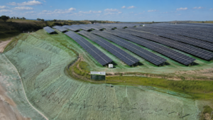 Usina fotovoltaica com taludes e áreas adjacentes cobertos por hidrossemeadura, promovendo revegetação e controle de erosão ao redor dos painéis solares.
