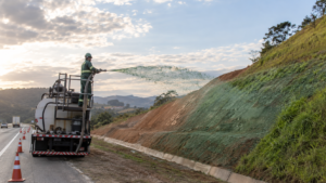 Operador da Agrega Verde realiza hidrossemeadura em talude de corte localizado ao lado de uma rodovia.